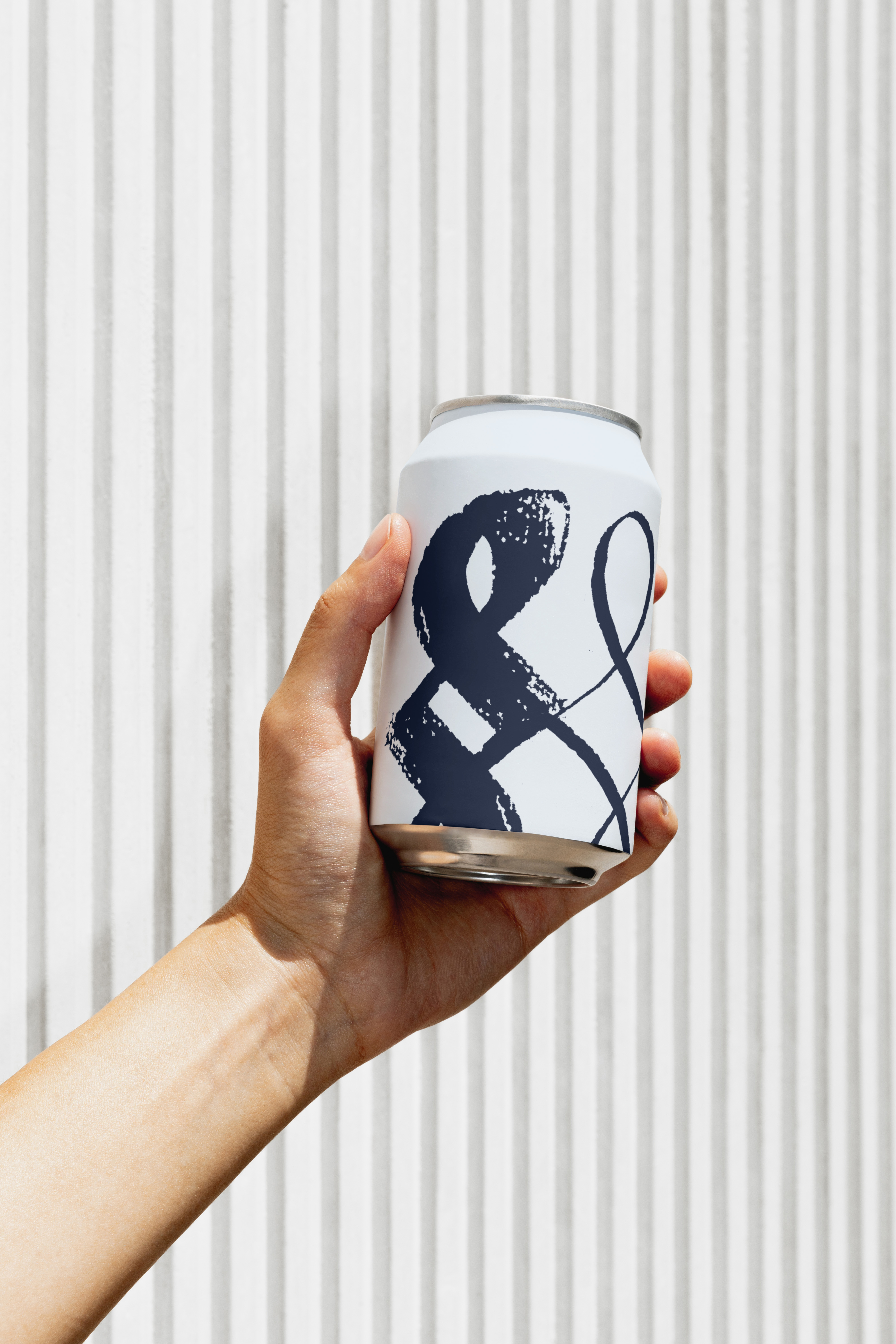 Hand holding a white beverage can with navy lettering